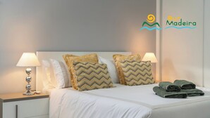 A neatly made bed with two pillows, a nightstand with a lamp, and a set of towels on the bed. - Quality tranquil villa with sea-view | OceanScape (Poiso)