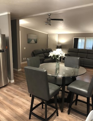 A modern kitchen with a dining table, chairs, a refrigerator, and a ceiling fan.