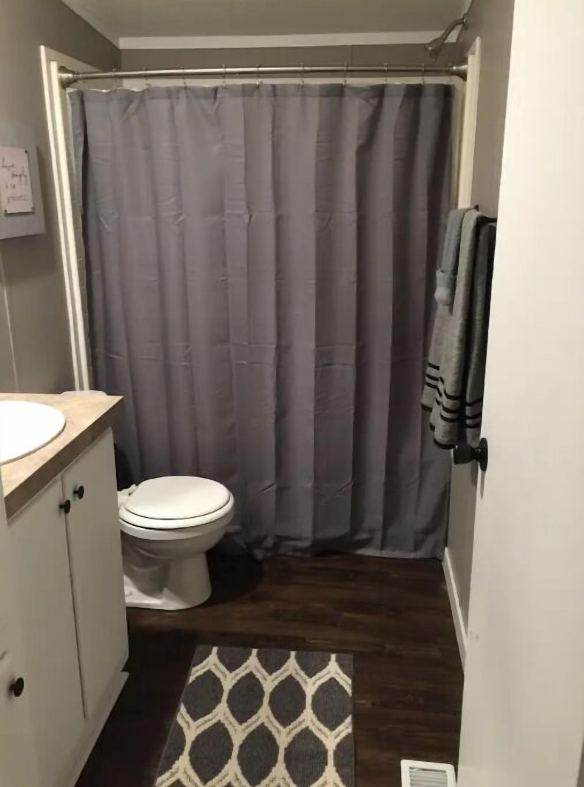 Een kleine badkamer met een toilet, een wastafel en een douchegordijn.