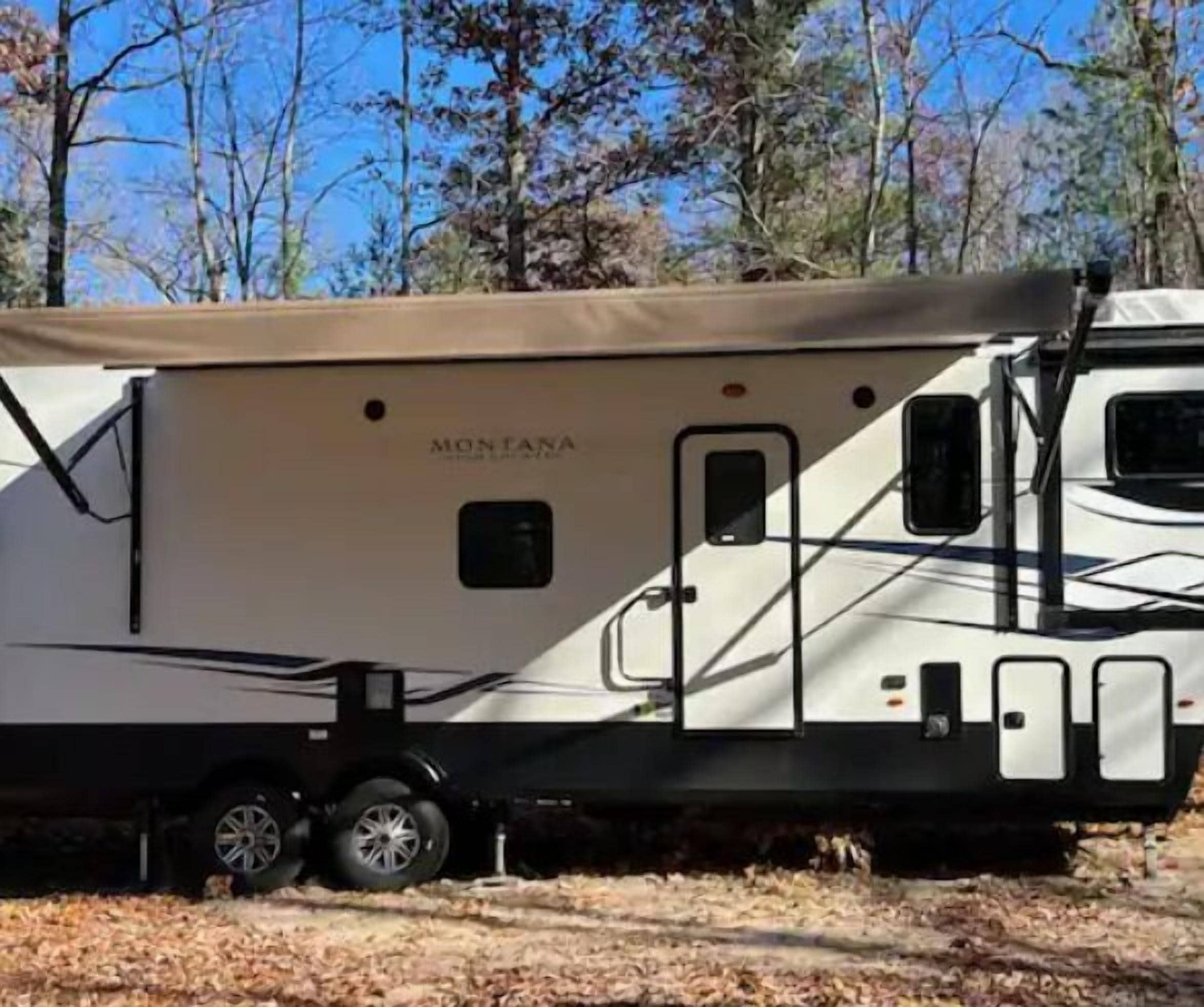 A large RV with a covered living area, a kitchen, and a bathroom.