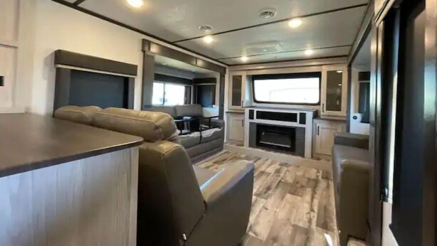 Interior moderno de una autocaravana con zona de estar, cocina y un amplio ventanal.
