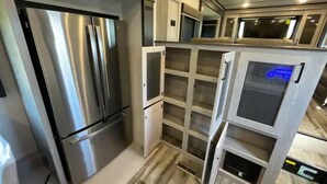 Una cocina compacta con electrodomésticos de acero inoxidable, microondas integrado y un refrigerador pequeño.