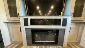 Una chimenea con pantalla digital, flanqueada por armarios de madera y un zaguán de madera.
