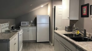 A compact kitchen with white appliances, a microwave, a refrigerator, and a sink. - quiet, cozy, country loft close to everything (Sherwood)