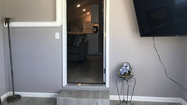 A room with a television mounted on the wall, a doorway leading to a living area, and a small table with a vase. - quiet, cozy, country loft close to everything (Sherwood)