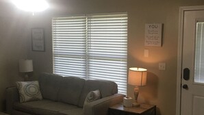 A living room with a sofa, a lamp, a door, and a window with blinds. - a cozy, quiet, rural hideaway close to everything3 (Sherwood)