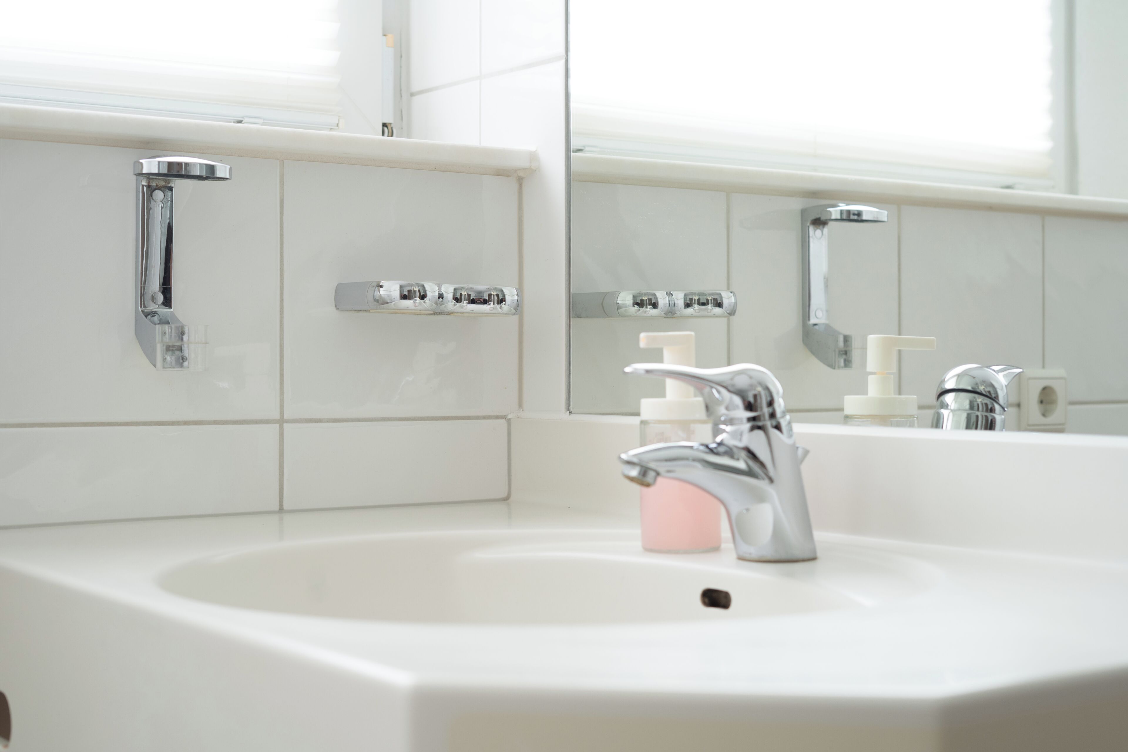 A bathroom with a white sink, chrome faucet, and a mirror above it.