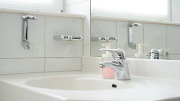 A bathroom with a white sink, chrome faucet, and a mirror above it.