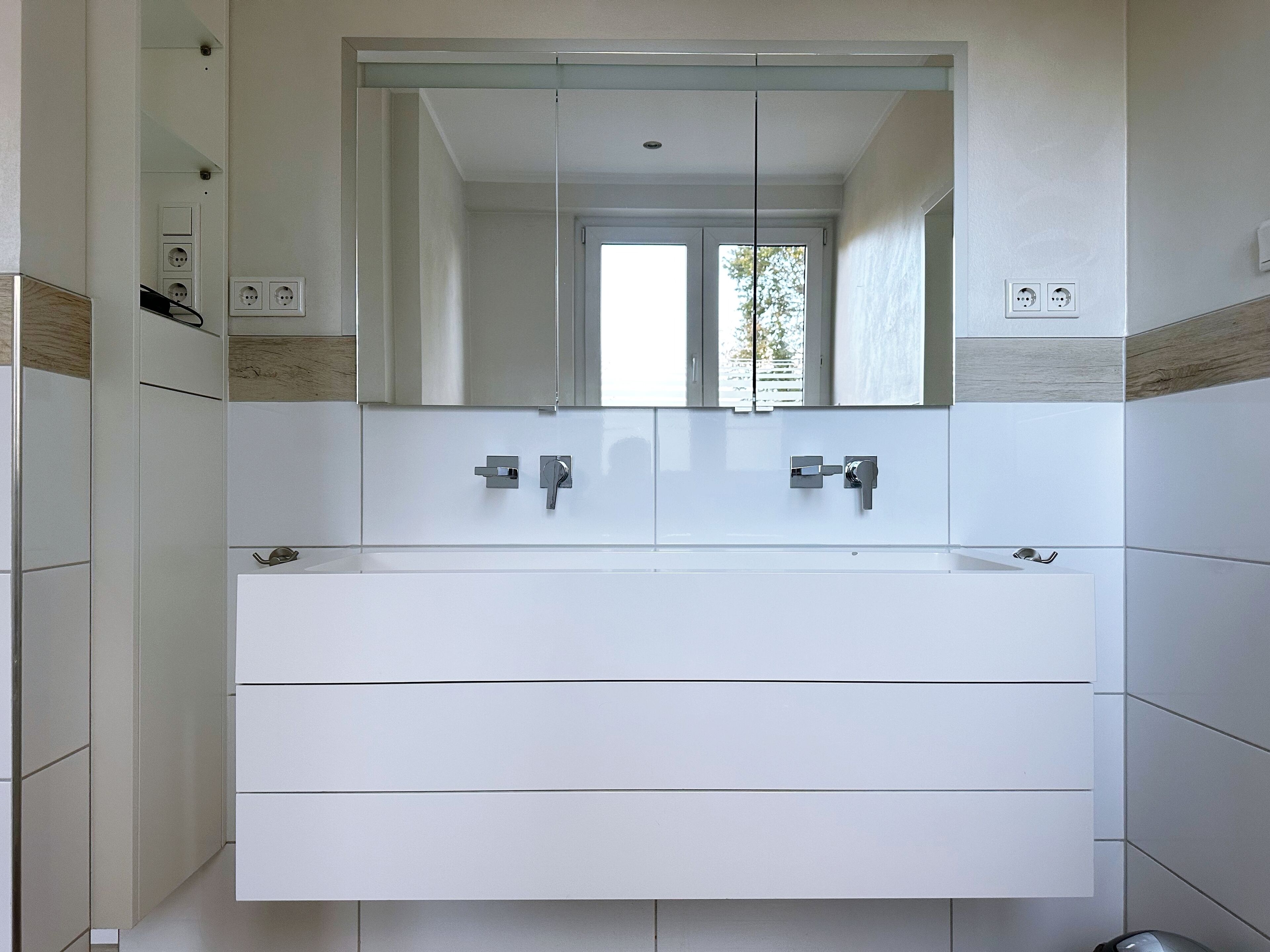 A modern bathroom with a large mirror, two sinks, and a walk-in shower.