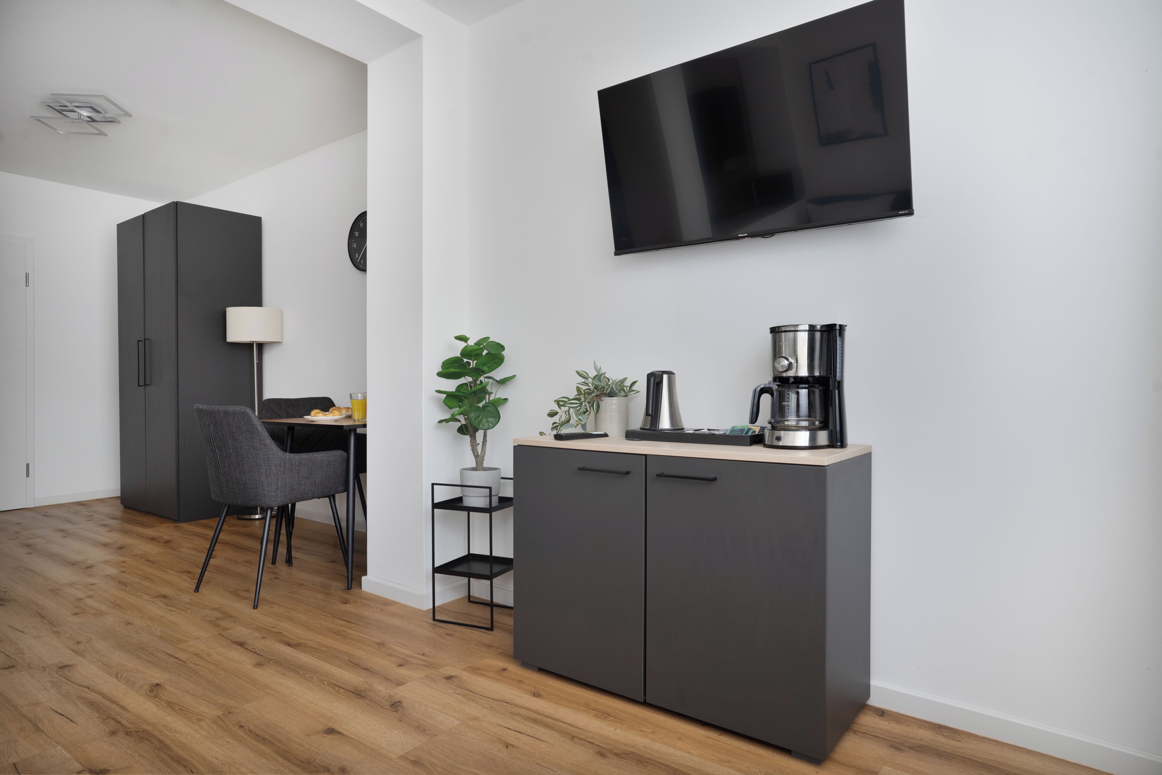 Une cuisine moderne équipée d’un téléviseur à écran plat, d’une machine à café et d’un coin repas avec une chaise et une table.
