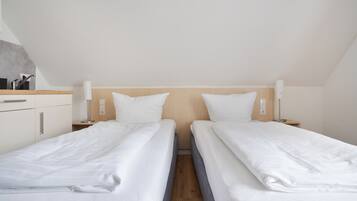 A twin room with two beds, a wooden headboard, bedside lamps, a small table, and a built-in cabinet.