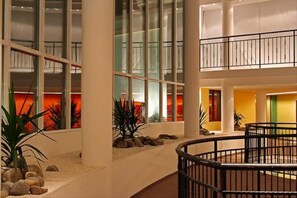 Experience the contemporary atmosphere of our multi-level atrium, featuring a central open area with a curved railing and large windows.