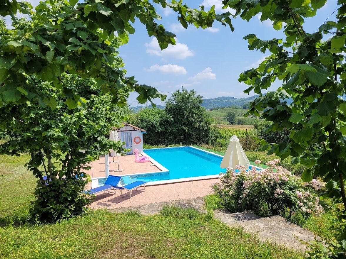 A swimming pool surrounded by lush greenery, with a small gazebo and lounge chairs.