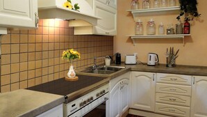A kitchen with white cabinets, a tiled backsplash, a stove, a sink, and a countertop with a coffee maker and a toaster. -  Silvio, Beautifully presented villa with own pool and hot tub. (Filicaia)