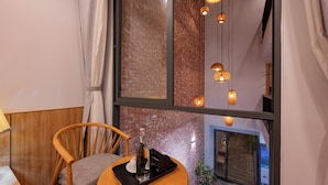 A cozy seating area with a wooden chair and a small table, a bottle, and a tray. - LaSanta Villa (Da Nang)