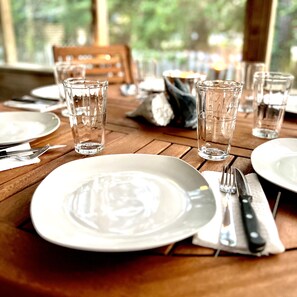 A wooden dining table set with plates, cutlery, and clear glasses. - Gas logs for a beautiful Winter Retreat (Ocracoke)