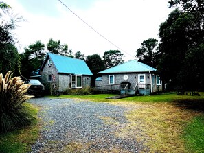 A two-story building with a blue roof, a front porch, and a gravel driveway. - Gas logs for a beautiful Winter Retreat (Ocracoke)