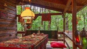 A rustic wooden cabin with a bed, a table with tea set, and a hanging lamp.