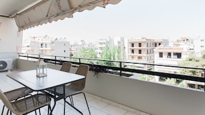Un balcon avec une table et des chaises, donnant sur un quartier résidentiel composé de différents immeubles.