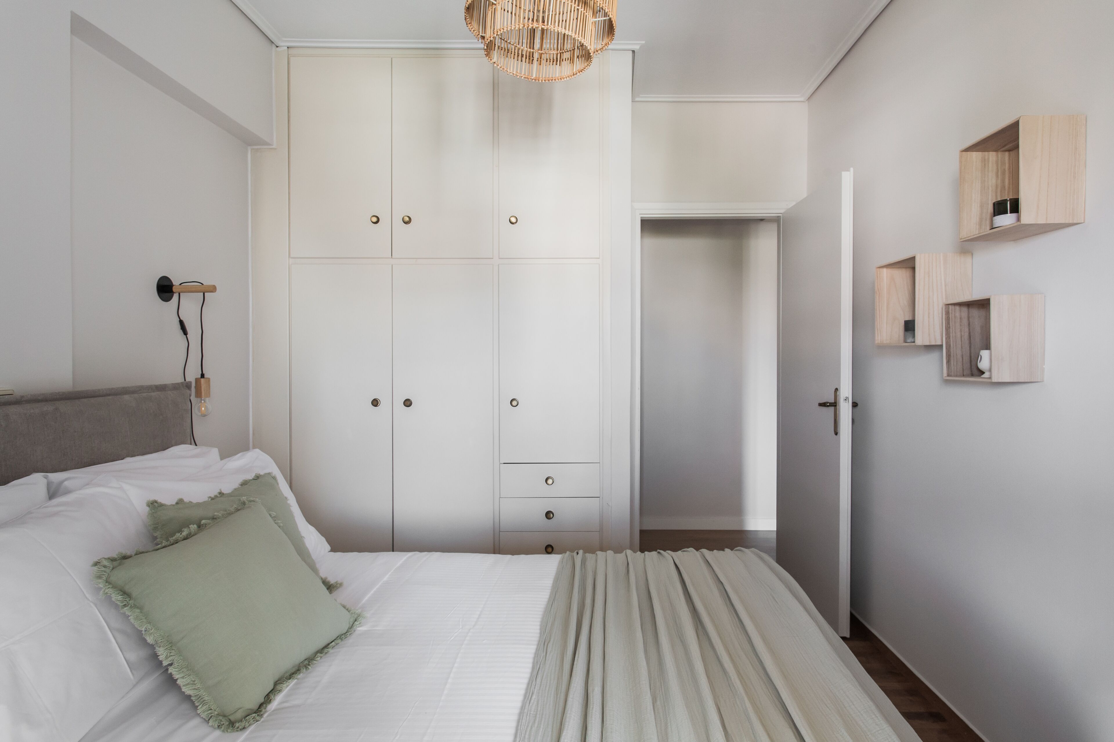 A bedroom with a bed, a wardrobe, and a bedside table.