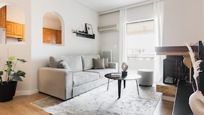 Un salon moderne avec un canapé gris, une table basse, une plante en pot et une cheminée.