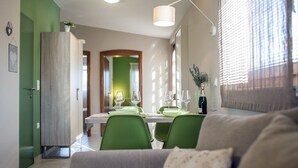 Ein modernes Wohnzimmer mit einer Couch, einem Essbereich mit Tisch und Stühlen sowie einer Küche im Hintergrund.