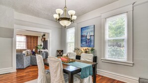 A dining area with a wooden table, white chairs, and a chandelier. There are large windows with blinds and a painting on the wall. - Walk to Crown Zellerbach Trl: PNW 'Celestial Inn' (Scappoose)