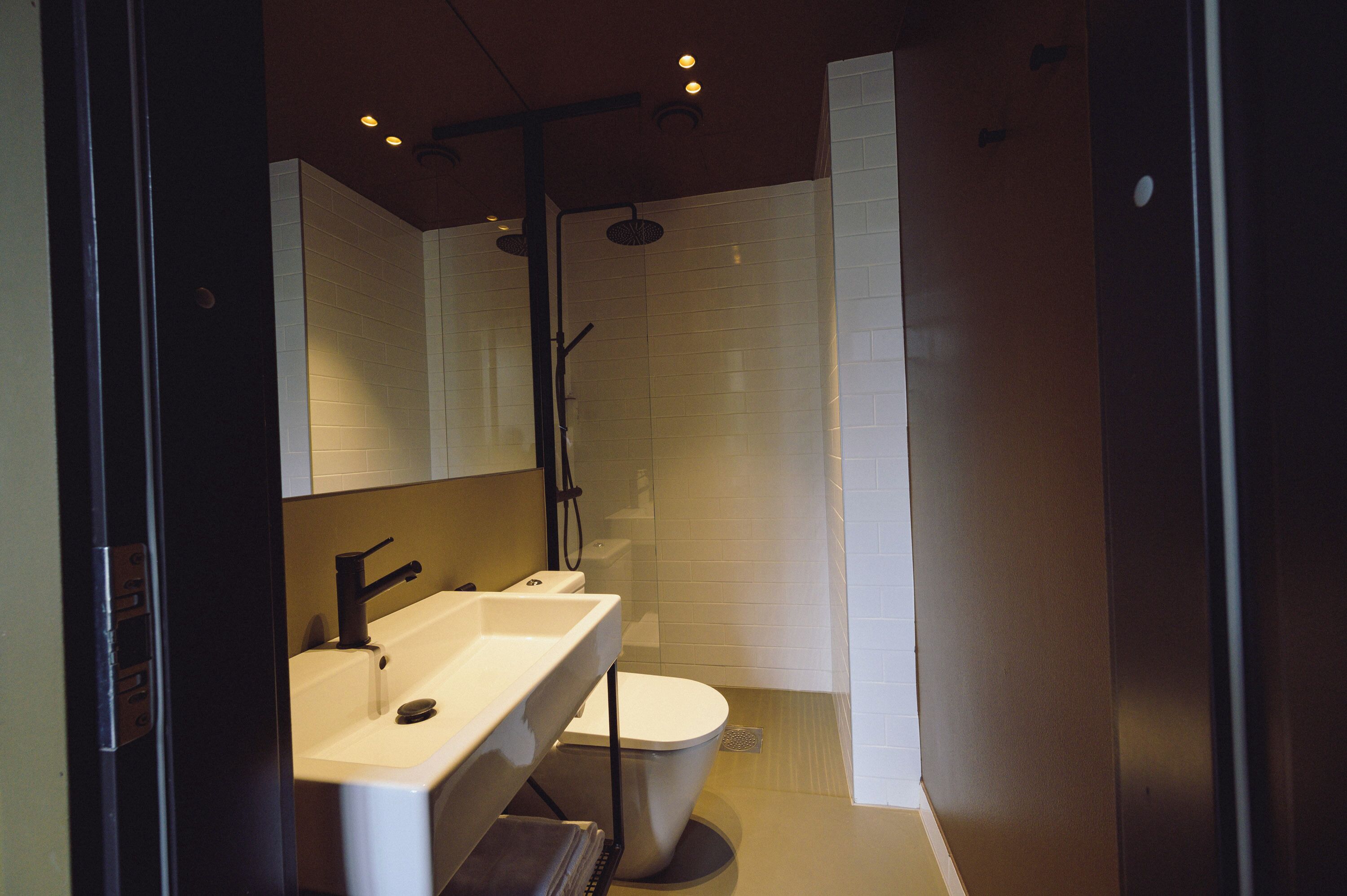 A modern bathroom with a large mirror, a sink, a toilet, and a shower.