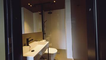 A modern bathroom with a large mirror, a sink, a toilet, and a shower.