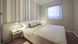 A bedroom with a bed, bedside table, lamp, and window with curtains. - apartment C - Red Apartment (Vir)