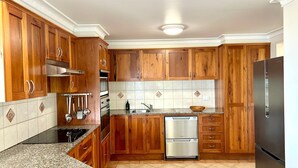 Une cuisine dotée de meubles en bois, d’un réfrigérateur en acier inoxydable, d’un lave-vaisselle et d’une cuisinière.