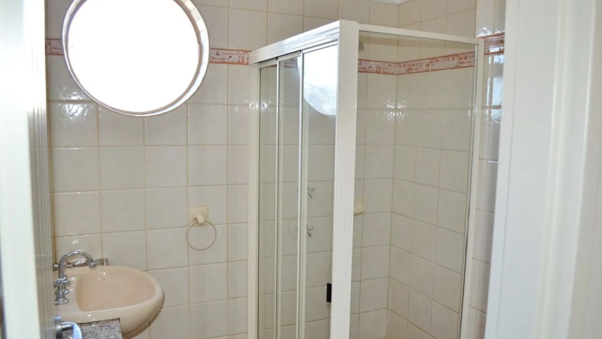 A bathroom with a sink, mirror, and glass shower enclosure.
