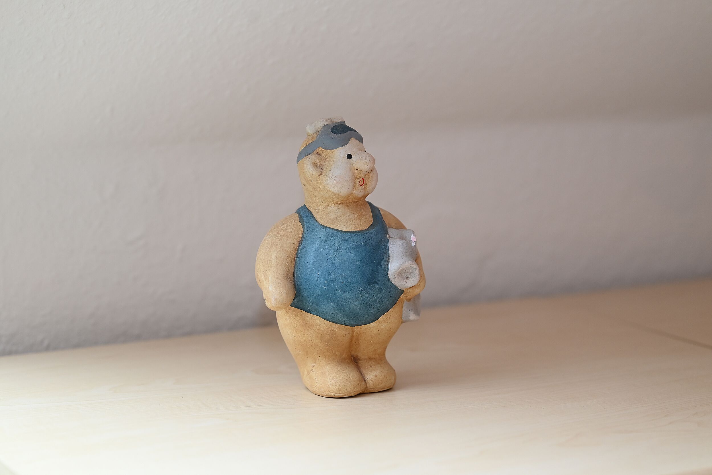 A small figurine of a person wearing a blue tank top and a cap, standing on a flat surface.