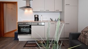 Una cocina compacta con armarios blancos, horno integrado y cafetera.
