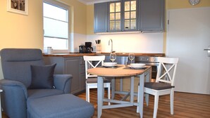Una cocina compacta con armarios grises, una mesa de madera y dos sillas.