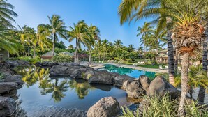 A tropical resort with a swimming pool surrounded by rocks and palm trees. - Mauna Lani Fairways #204: Tropical Home w/spa, lanai, lagoon pool & activities (Kamuela)