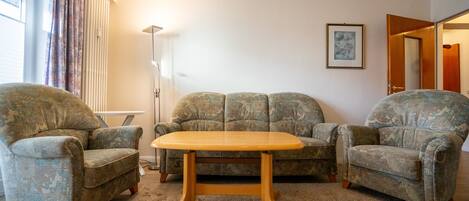 A living room with a sofa set, a coffee table, and a floor lamp.