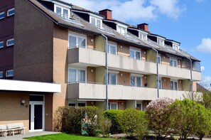 A multi-story residential building with a flat roof, balconies, and a small garden area with benches. - Hus Willem I/19 in Ruhiger Lage (Büsum)
