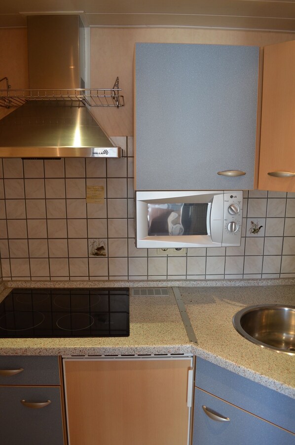 A kitchen with a built-in microwave, stainless steel range hood, and a sink. - Hus Willem I/19 in Ruhiger Lage (Büsum)