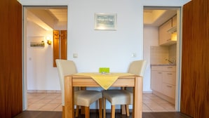 Un comedor con una mesa de madera y dos sillas, un mantel amarillo y un cuadro en la pared.