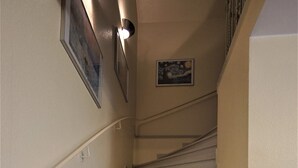 Eine Treppe mit Handlauf, Teppichstufen und Wandleuchten.