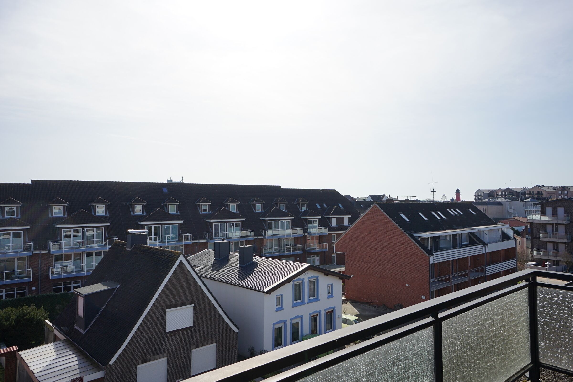 A residential area with multiple two-story houses, some with balconies and solar panels, under a clear sky.