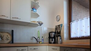 Una cocina compacta con armarios blancos, horno integrado y ventana con cortina.