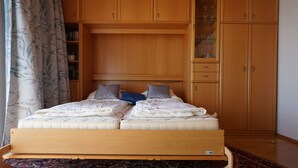 Un dormitorio con una cama de madera, un tapete estampado y armarios de madera.