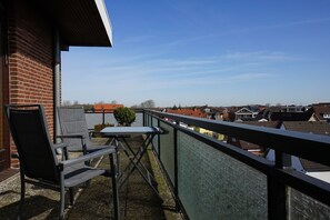 Een balkon met een tafel en stoelen, met uitzicht op een woonwijk.