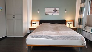 Ein Schlafzimmer mit einem Bett, zwei Nachttischen mit Lampen, einem Bild an der Wand und einem Kleiderschrank.