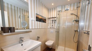 Ein modernes Badezimmer mit einer Duschkabine, einem weißen Waschbecken und einer Toilette.