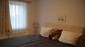 A bed with a patterned bedspread, a pillow, and a cat. - Residenz Rosenhof BDH (Büsumer Deichhausen)