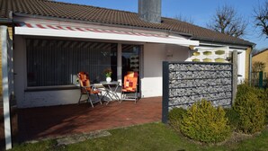 Ein Haus mit überdachter Terrasse, Garage und umzäunter Garten.