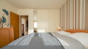 Ein Schlafzimmer mit einem Bett, einem Kleiderschrank und einer Tür zu einem anderen Raum.